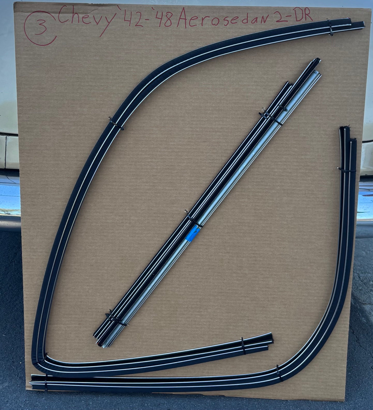 1942–1948 Chevy two-door Fleetline Aerosedan window channel kit with formed run channels and straight components arranged on a cardboard board.