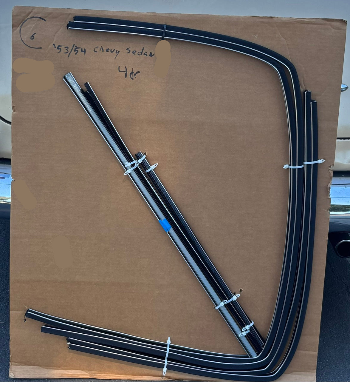  1953–1954 Chevy four-door sedan window channel kit with formed run channels and straight components arranged on a cardboard board.