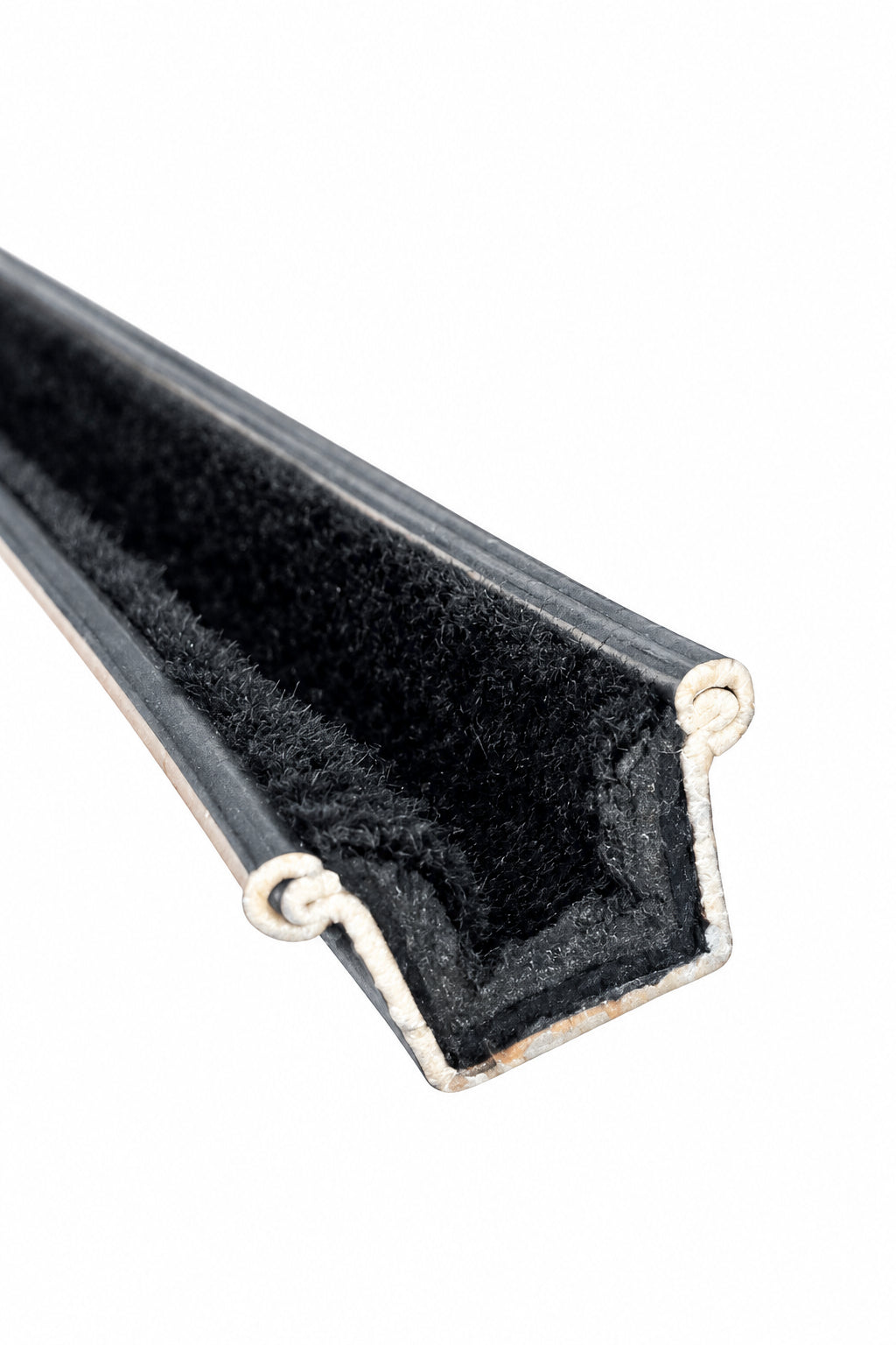 Close-up of a rigid division bar showing the black fuzzy channel and metal profile at the cut end.